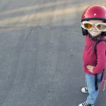 Young boy dressed in a red rocket suit on blacktop